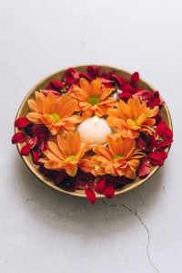 A candle surrounded by flowers in a bowl.