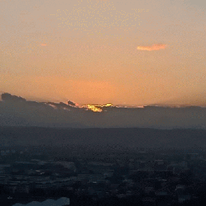 The sun rising over some clouds which are next to the horizon.