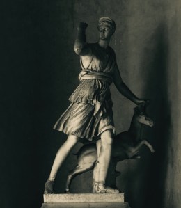 A stone statue of the goddess Artemis reaching back for an arrow in her quiver.