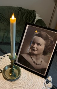 Ancestor altar including a framed photograph of a woman and a white taper candle.