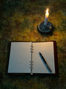 My book of shadows opened to a blank page of lined paper illuminated by a candle.